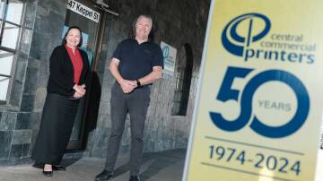 Lisa Mallon and Peter Wright standing outside of Central Commercial Printers, with a 50 year banner. Picture by James Arrow.