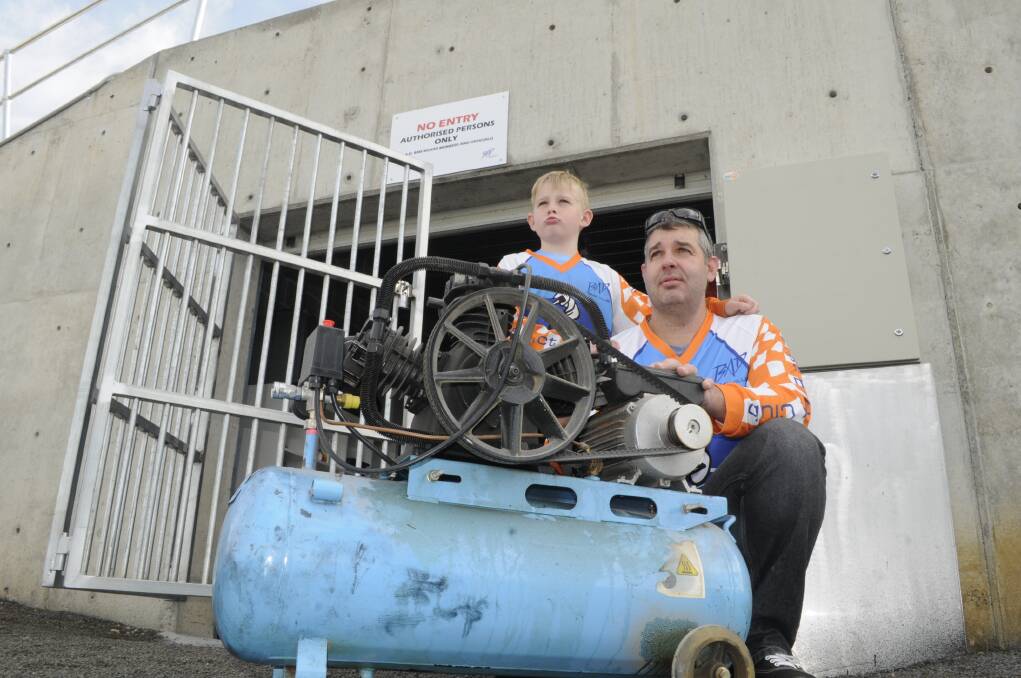 HEARTBREAKING: Bathurst BMX Club’s Bradley Martin, 9, and his dad Phillip with the club’s old compressor which was left behind when thieves stole thousands of dollars worth of equipment from the new facility. Photo: CHRIS SEABROOK 	062616cbmx1