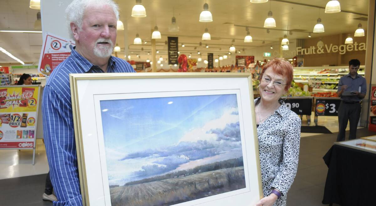 POPULAR VOTE: Artist Greg Cross with his painting "Approaching Storm", which won the people's choice vote, and Merilyn Rice of Merilyn Rice Studio. Photo: CHRIS SEABROOK 112816craffle1