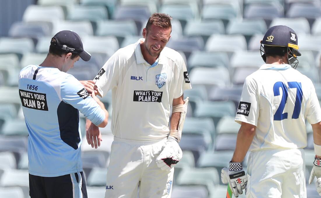 OUCH: Trent Copeland is seen by medical staff after injuring his right arm during day three of the Sheffield Shield match between his Blues and Western Australia at the WACA. Photo: AAP