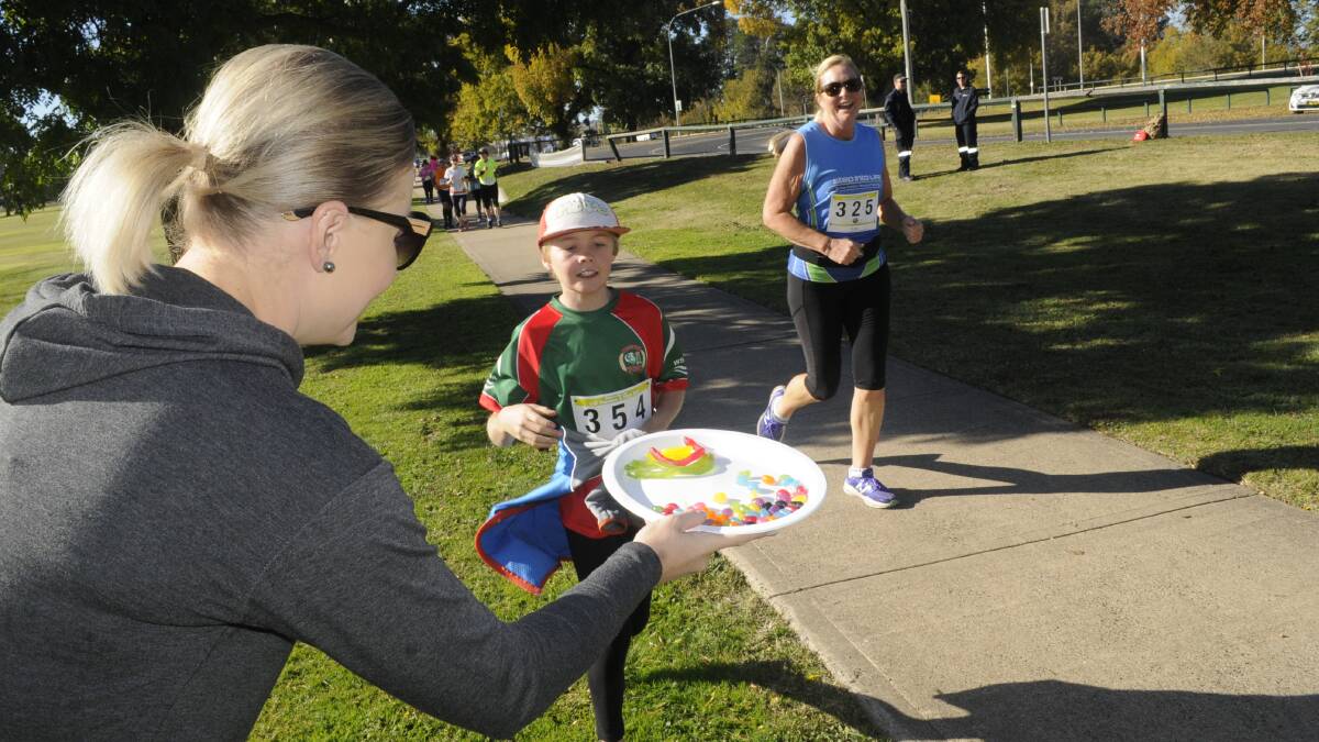 SUGAR HIT : Elissa Dove from Bathurst Runners Club offers Miles Heller some lollies during Sunday's 10km run. Photo:CHRIS SEABROOK 050716c Marathn