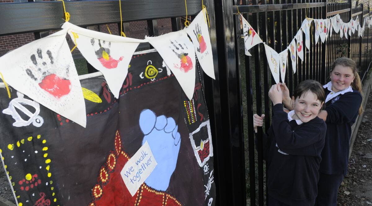 HANDS UP: Bathurst Public School students Amy Mounce-Stephens and Leilani Dawes with the NAIDOC Week bunting. Photo: CHRIS SEABROOK 062916cnaidoc