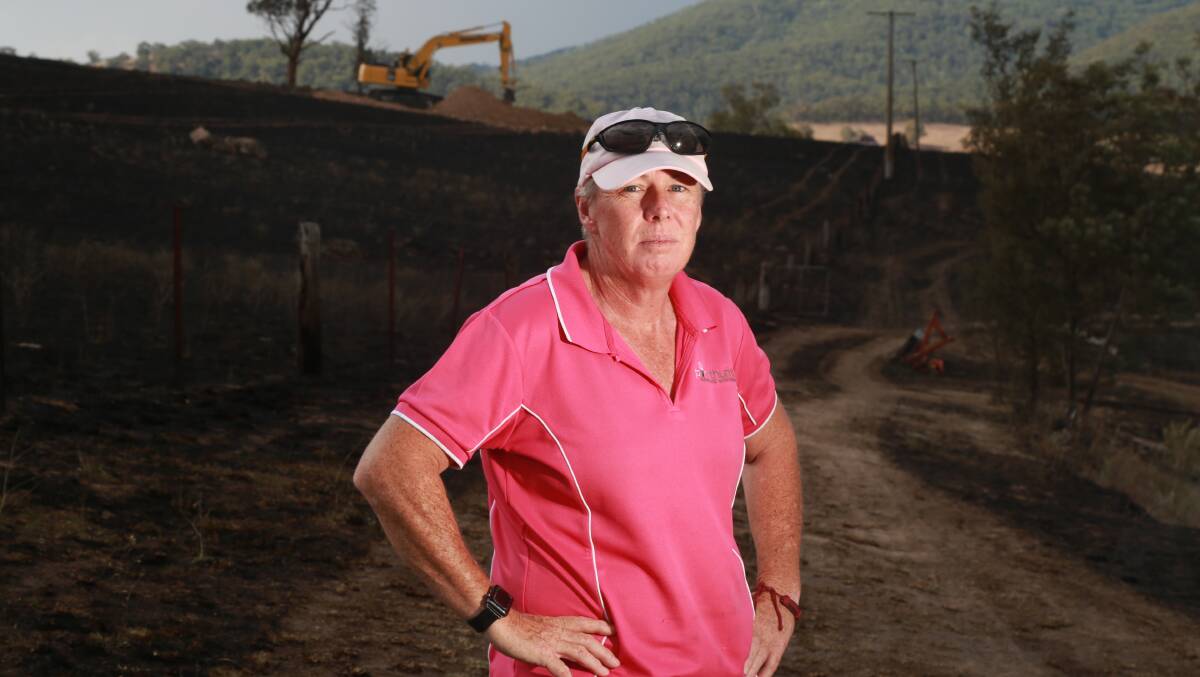 GRASS FIRE: Sue Tracy at her Sodwalls property, the digger at back of the image is burying sheep which were killed in Thursday's fire. Photo: PHIL BLATCH