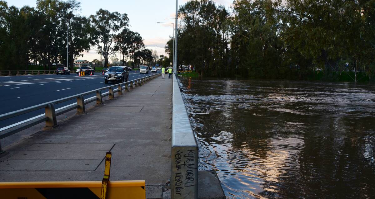 Threatened: Council workers monitor water levels at the Emile Serisier Bridge on Saturday afternoon, ahead of the predicted peak on Saturday night. Photo: PAIGE WILLIAMS