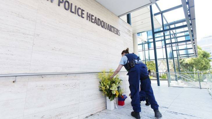 A police officer lays flowers at in tribute to Curtis Cheng, who worked for the police finance department. Photo: James Brickwood