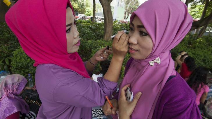 Nurjanah, who works as a maid in Hong Kong, helps a colleague with makeup on their day off. Photo: Alex Hofford