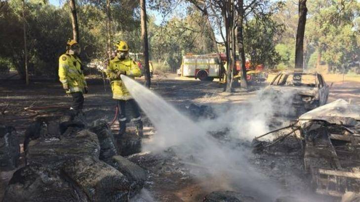 Firefighters hose down a burnt-out ute during the Waroona bushfire. Photo: ABC