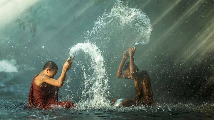 Young Buddhist monks splash each other during Songkran.