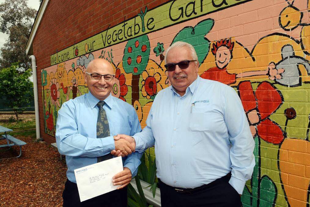 EYE IN THE SKY: Bathurst South Public School principal Greg Cross thanking Reliance Credit Union Reliance regional development manager Mark Haley for a grant to help protect the school's new chickens. Photo: PHILL MURRAY 102114preliance