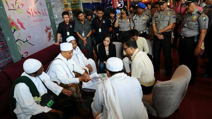 Police look on at a Surabaya shopping centre as centre staff sign a document promising not to dress employees in Christmas apparel. Photo: Robertus Pudyanto