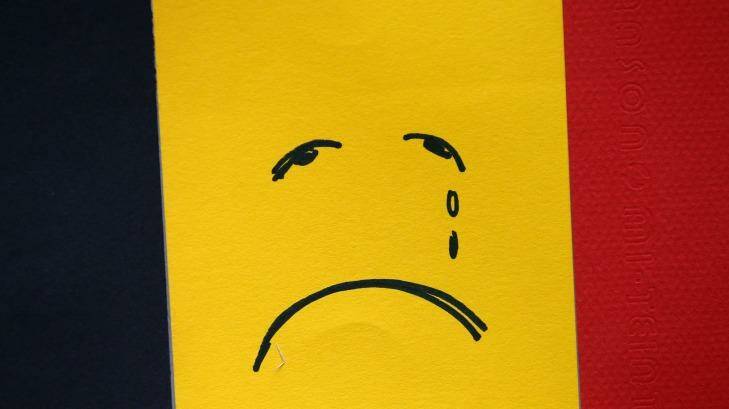 A sad face is drawn on a Belgian flag near Maelbeek metro station after Tuesday's attack. Photo: Carl Court