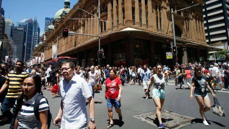 Pedestrians cross George Street in front of the Queen Victoria Building in Sydney. Photo: Daniel Munoz