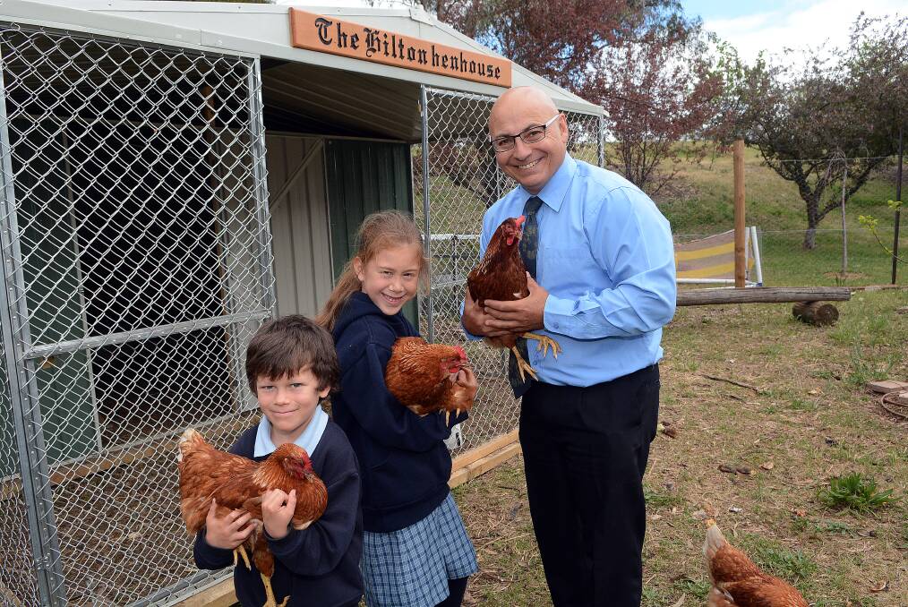 EGG-CITING TIMES: Bathurst South Public School principal Greg Cross with students Keira Blaikie, seven, and Marcus Lewin, eight, show off some of the school's new chickens donated following a vicious attack at the school earlier this year. Photo: PHILL MURRAY	 102114pchooks