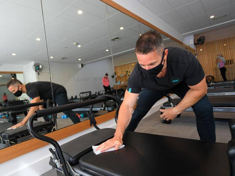 Owner of KX Pilates Aaron Smith cleans down equipment after reopening his studio in Melbourne.