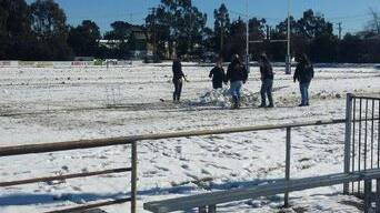 WINTER WONDERLAND: Officials try to clear snow from the field in Oberon on Saturday. Photo: WESTERN RUGBY LEAGUE
