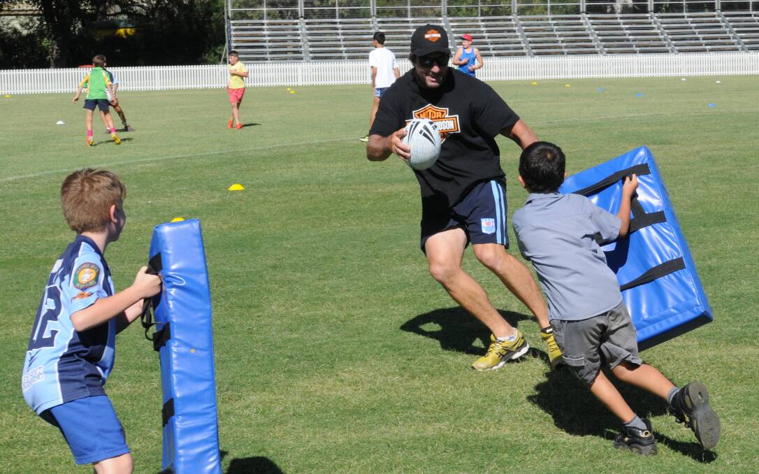 LOOK OUT: Nathan Hindmarsh tries to dodge a couple of eager school kids during yesterday's junior clinic. Photo: MARK LOGAN