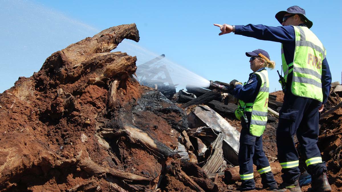 DUBBO: Members of Dubbo Fire and Rescue work to mop up a blaze that burned for four hours in a pile of railway sleepers and rubbish. Photo FIRE AND RESCUE NSW