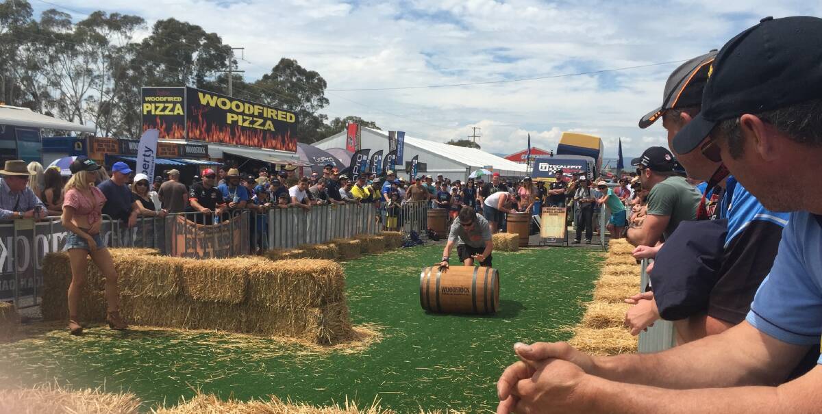 COURSE WITH A DIFFERENCE: The barrel racing course, run by Woodstock Bourbon, has a big crowd in the Bathurst 1000 merchandise alley today. Participants were timed as they rolled a barrel around a course avoiding a number of hay bales. Photo: NADINE MORTON