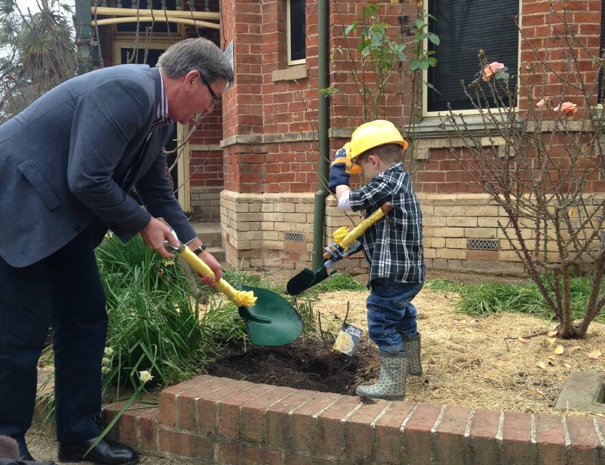 HARD WORK: Bathurst mayor Gary Rush and 4-year-old Harvey Hitchick planting the celebratory rose in the rose garden at Machattie Park on Thursday. Photo: Emily Foster 