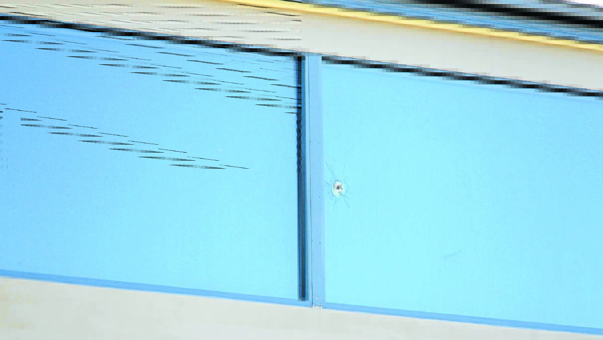 TRAGEDY: A bullet hole is visible in one of the home's windows. 