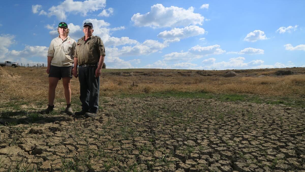 DRY TIMES: Local farmer David McKay and his son Hamish with a bone-dry dam on their property. The farming family is feeling the effects of above-average temperature and below-average rainfall during the last three months. Photo: PHIL BLATCH 	041216pbdam4