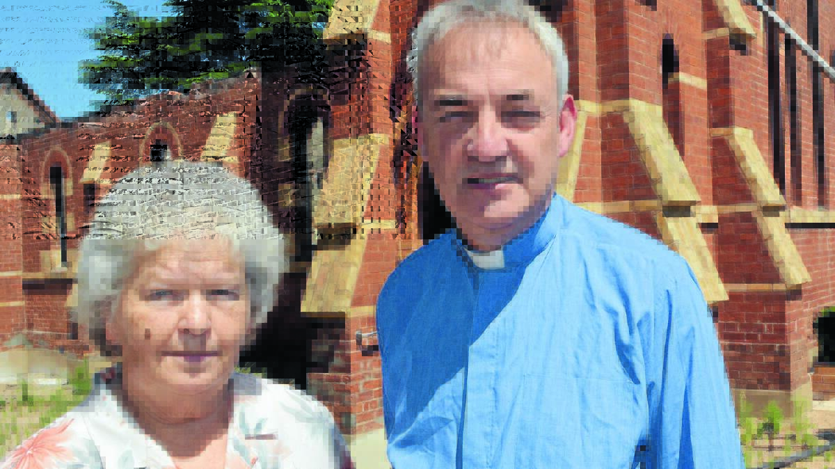 AN EXCITING TIME: St Barnabas’ Church spring fete organiser Bev Walsh with Fr James Hodson outside the gutted church this week. Photo: PHILL MURRAY 	111314pstbarn