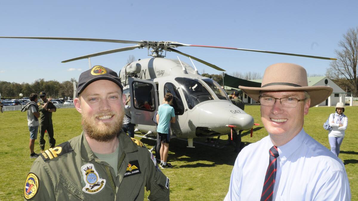 COME FLY WITH ME: Pilot Lieutenant Mitchell Sanders RAN and All Saints College Headmaster Dr Peter Miller with a Navy Bell 429 medium utility helicopter which attracted a lot of attention at the College’s Spring Fair. Photo: CHRIS SEABROOK.	 091315casc1