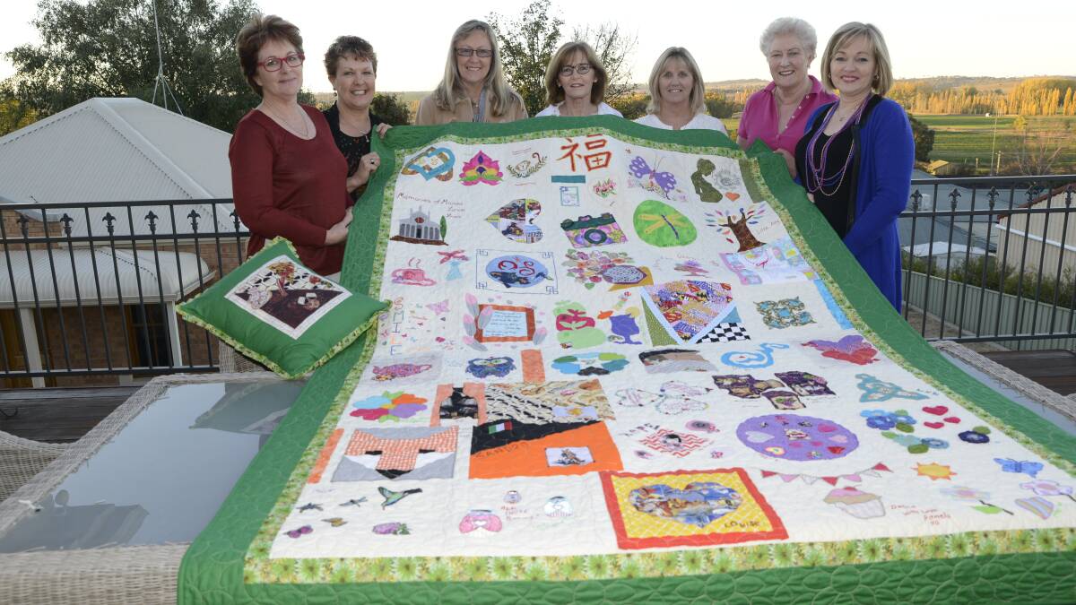 THANK YOU: Linda Aldwinckle, Mary-Anne Ford, Lorrae Sullivan, Donna Baldi, Margaret Picken, Fran Hanger and Susannah Robinson with the handmade quilt that Donna’s workmates made for her after she was diagnosed with a malignant tumour. By PHILL MURRAY 	050516donna