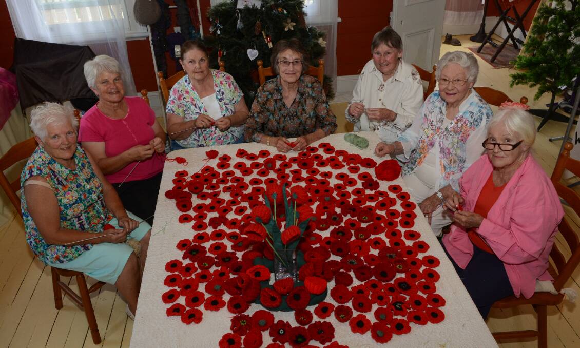 BLOOMING: Barbara Glossop, Judy Dalitz, Mary Miller, Robin Bell, Judy Windsor, Loris Wells and Wendy Woods with the poppies they have knitted as a tribute to diggers. Photo: PHILL MURRAY	 120814ppoppies1
