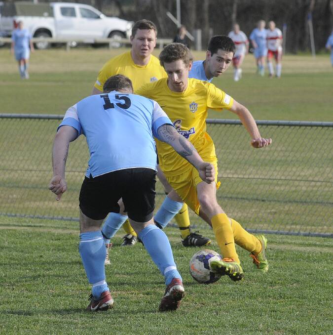 FOCUS: Abercrombie FC’s Bree Gowland tries to work his way around City Colts defender Aaron Paterson (#15) in their Bathurst District Football men’s first grade match on Sunday. Photo: CHRIS SEABROOK 	072014cmsoc5