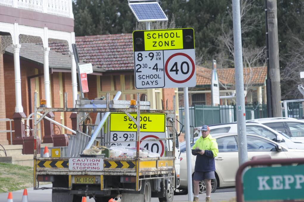 BIG WARNING SIGN: A technician prepares to switch on the newly installed flashing school zone sign on the approach to the Cathedral School in George Street on Tuesday afternoon. Photo: CHRIS SEABROOK 	081115c40ks2
