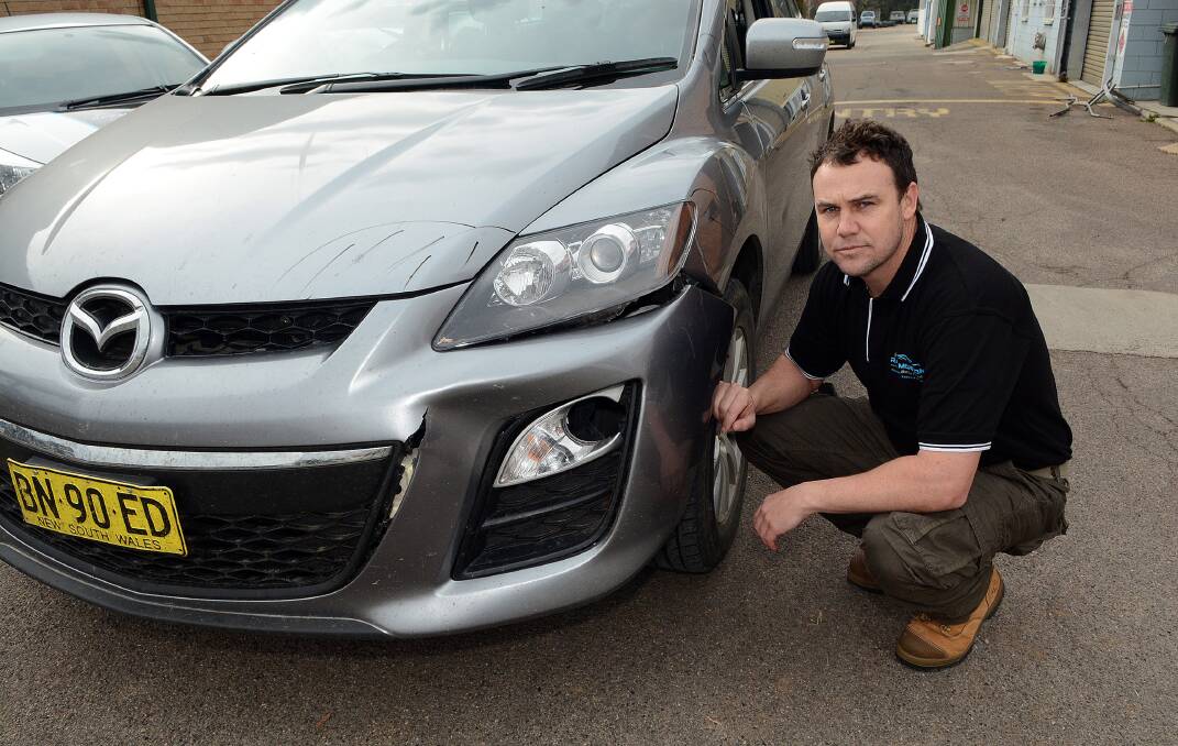 DAMAGE: Bathurst smash repairer Andrew Morcom with a car which collided with a kangaroo. 	072414pskippy