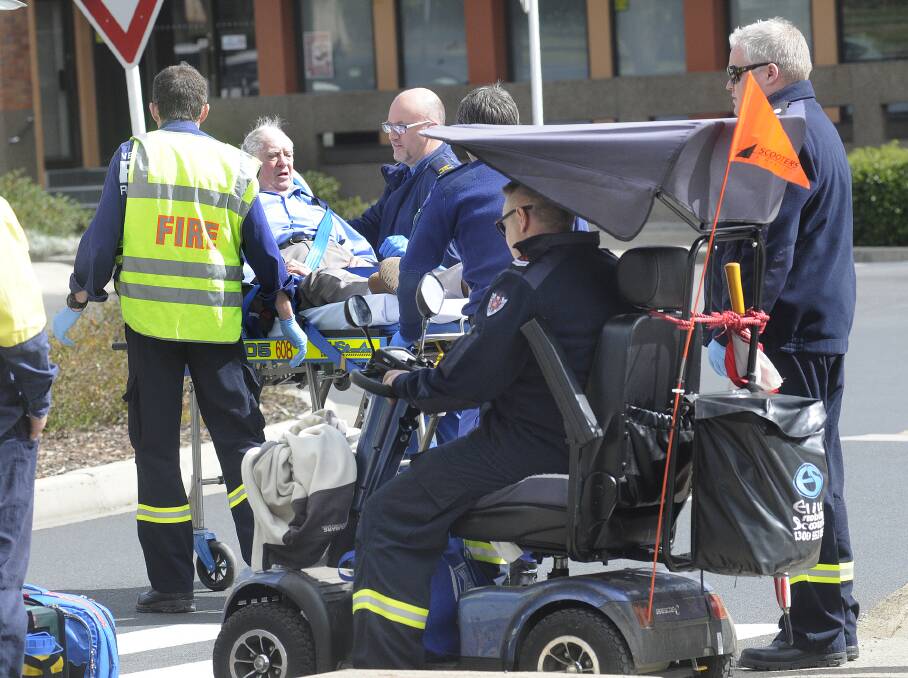 NASTY SPILL: Paramedics and Bathurst Fire Station personnel assist an elderly man who came off his mobility scooter yesterday. 	082614cscootr3