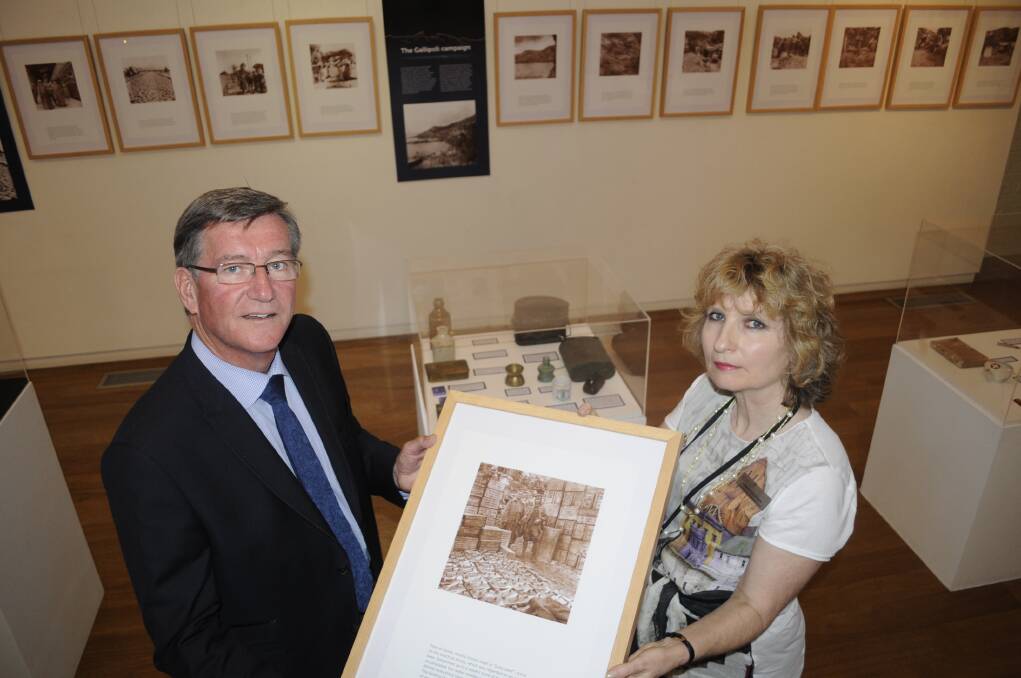 HAUNTING INSIGHT: Mayor Gary Rush with Linda Coleman, from the Australian Fossil and Mineral Museum, holding a photo of “Bully Beef” supplies that were placed on the beach during the Gallipoli campaign. The photo is one of the many taken by Sir Charles Ryan. Photo: CHRIS SEABROOK 040315cexhib1