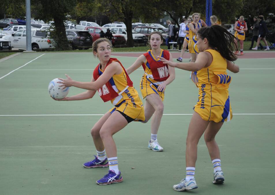 BATTLE OF BATHURST: Bathurst under 17s player Carina Floyd with team-mate, Frances Orman in support, looks for a chance to get past an under 21s defender in her team’s 16-13 defeat yesterday. Photo: CHRIS SEABROOK 	042615cnetb3