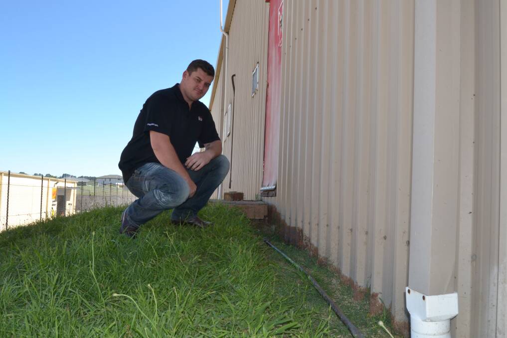 ENTRY POINT: Harvey Norman franchisee Beau Lane inspects the point where intruders broke into the retailer early yesterday morning. A large crowbar, which they used to force open the door, was left behind on the ground nearby. Photo: JACINTA CARROLL	 020816jharvey1