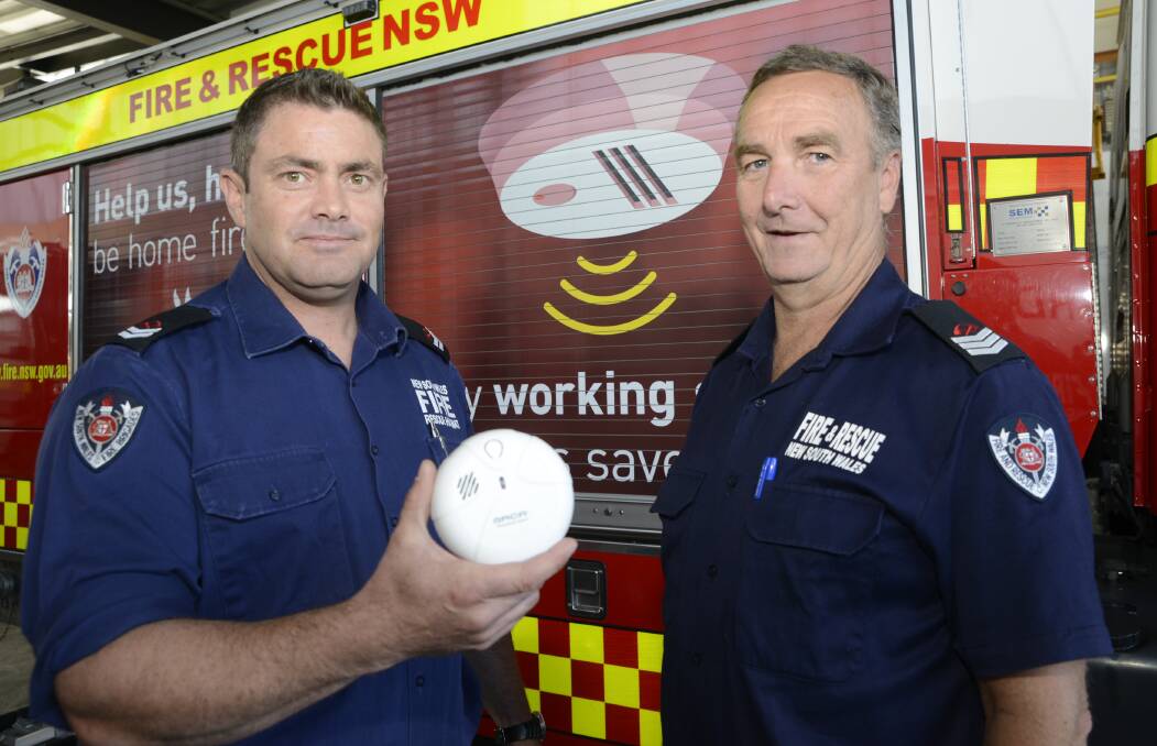 NEW TECHNOLOGY: Bathurst Fire and Rescue NSW Senior Firefighters Mal Bird and Paul Phegan showing one of the new breed of smoke alarms that are now available in time for the expiry of many people’s household smoke alarms. Photo: PHILL MURRAY 041516pfire