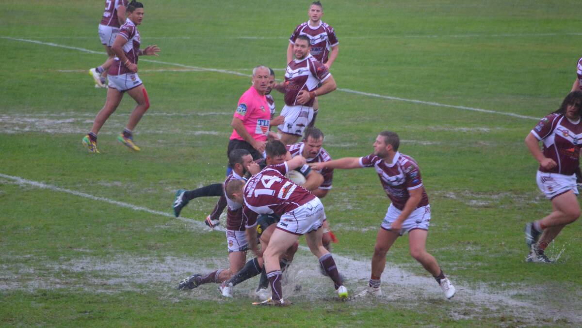 HARD TO EVALUATE: Panthers player-coach Todd Barrow is wrapped up by a swarm of Blayney defenders yesterday in the wet at King George VI Oval. Photo: SAM DEBENHAM 041716sdPanthers4