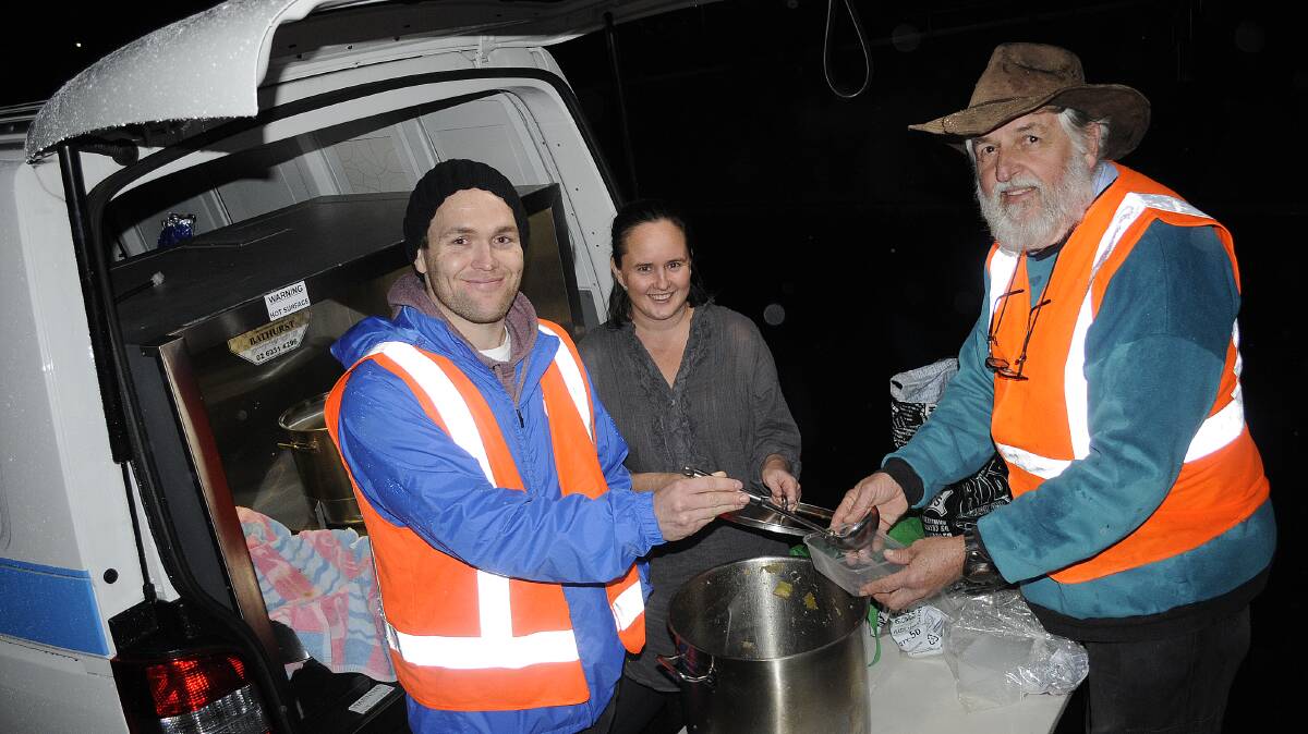 COME AND GET IT: Bathurst Tucker Van volunteers James Collins, Fiona Innes and Aivars Klavins were dishing up chicken and beef soup outside the Kelso Community Centre on a cold and wet Saturday night. Photo: CHRIS SEABROOK 	081614csoup