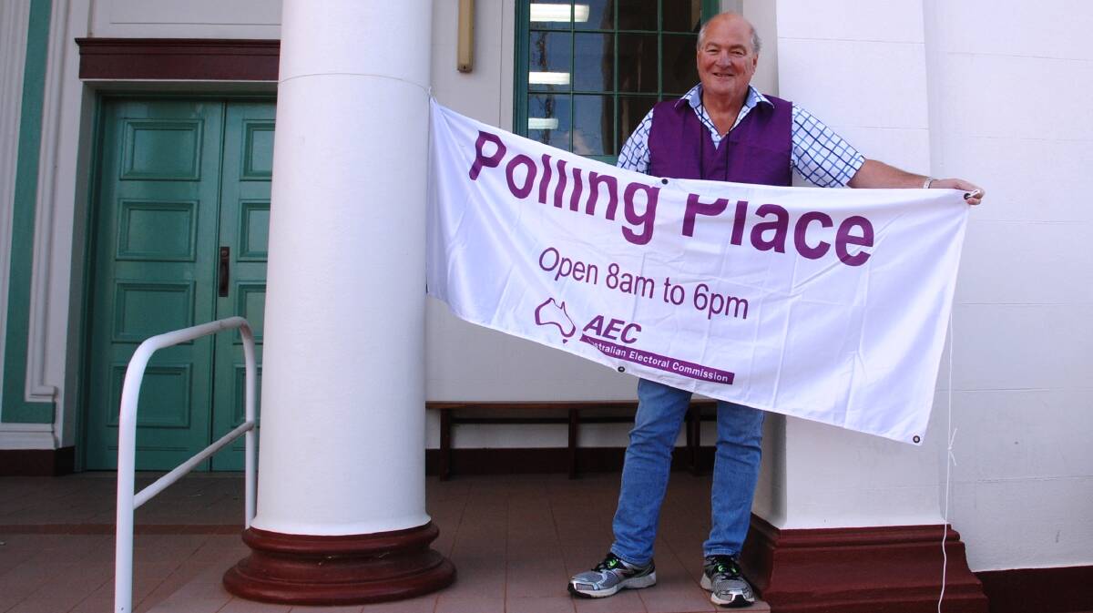 Chief polling officer at the Merredin court house, Martin Morris, prepares to hang the polling place identification banner at 7.30am before the poll opened.