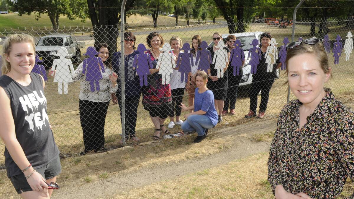 TAKING A STAND: Family Violence Awareness Group vice chair Temeka Jones, member Yasmin Dowling and treasurer Annelie Watt join other members in erecting cut-outs at Carrington Park to mark White Ribbon Day yesterday. Photo: CHRIS SEABROOK 112415cwomen