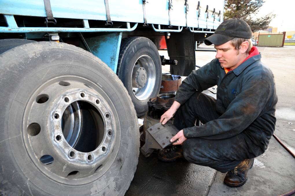 STOP-START: Burke’s Transport heavy vehicle diesel mechanic Josh Bravenboer inspects brake shoes on a company truck. Business owner Graeme Burke says trucks on the Bathurst to Sydney run need new brakes every 70,000 to 100,000km. Photo: ZENIO LAPKA 060214zburkes1