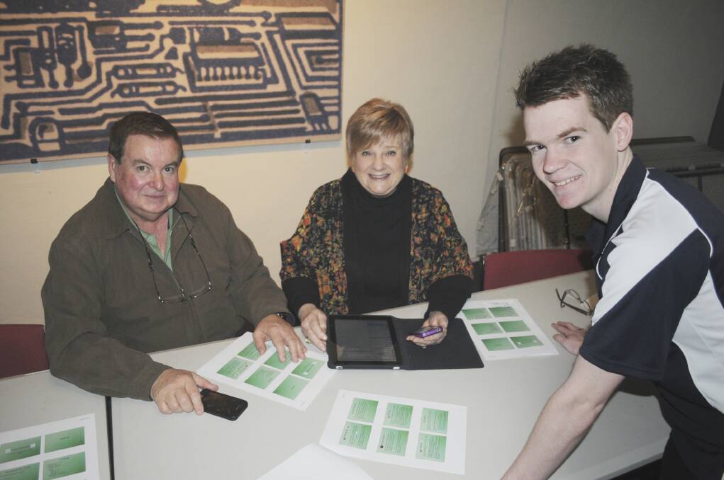 TECH SAVVY: Noel and Eve Scoffield get hands-on advice for their iPad and iPhone from Tech Savvy trainer Rohan Fahey at the library’s booked-out course. Photo: CHRIS SEABROOK  090114capps3