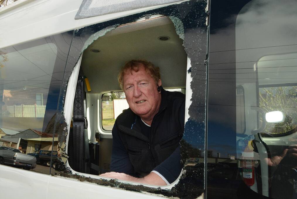 JUST SMASHING: David Graham from EnhanceABILITY with one of two Carenne School buses that had their side windows smashed by vandals this week. Photo: PHILL MURRAY 081214pbus