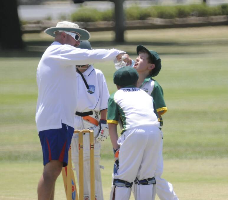 A REAL SCORCHER: A parent brings out cold water to the Bathurst U12’s team members in the Blue Mountains versus Lithgow match at Morse Park yesterday. Photo: CHRIS SEABROOK 112314csnap