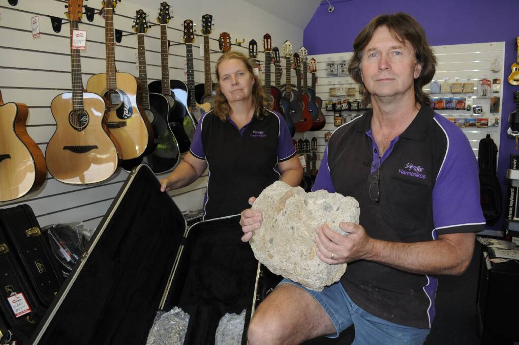 DISCOURAGED: Cath and Phil Snitch from Harmonikos have been left feeling discouraged after a break-in and theft from their family-run store on Monday night. They are pictured with the rock that was thrown through the shop window. Photo: CHRIS SEABROOK                    020315c