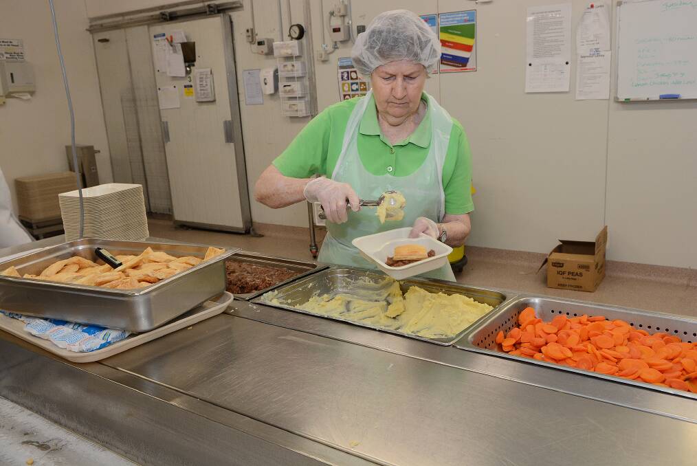 DEDICATION: Meals on Wheels volunteer Pat Cox at work preparing meals to be delivered this week. She is one of hundreds of dedicated volunteers who have helped run the service for the last 50 years. Photo: PHILL MURRAY 111114pmeals