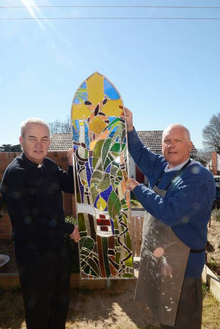 TRUE COLOURS: Priest in charge of St Barnabas’ Church, Father James Hodson, admires the work done by Father Paul Woodhart in recreating a POW memorial window salvaged when the church was destroyed by fire in February. Photo: PHILL MURRAY 081414plights