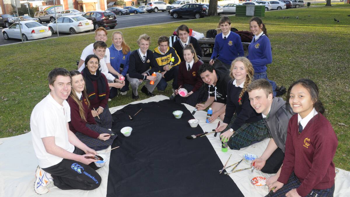 BLACK LIGHT REACTIVE: Members of the Bathurst Youth Council gathered in Machattie Park late yesterday to paint a banner to promote Friday’s Black Light Night event. Photo: CHRIS SEABROOK 072015cyouthc