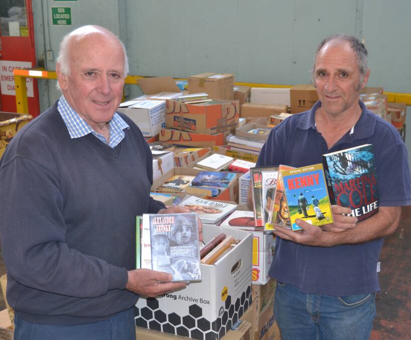 BOOK BONANZA: Lifeline executive officer Alex Ferguson and volunteer Bill Miller with some of the 22,000 books and DVDs in this weekend's Mega Book Fair. Photo: NADINE MORTON 102016nmbooks3